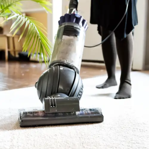 Lady vacuuming rug | Shans Carpets And Fine Flooring