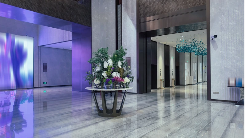 Luxurious hotel lobby with a sophisticated design. The lobby features a grand entrance with high ceilings and a polished marble floor that reflects the ambient lighting.