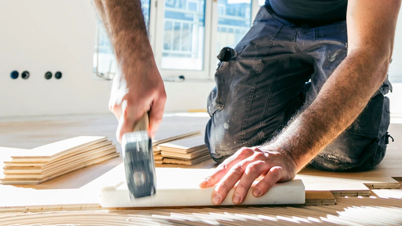 Worker laying parquet flooring. Worker installing wooden laminate flooring