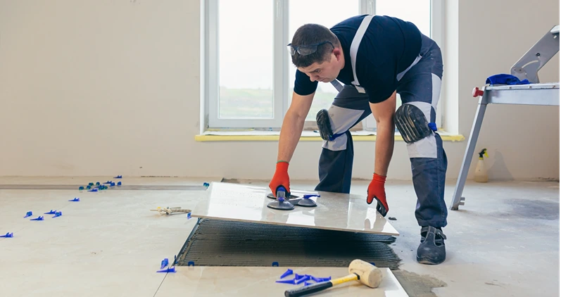 A male construction worker installs a large ceramic tile