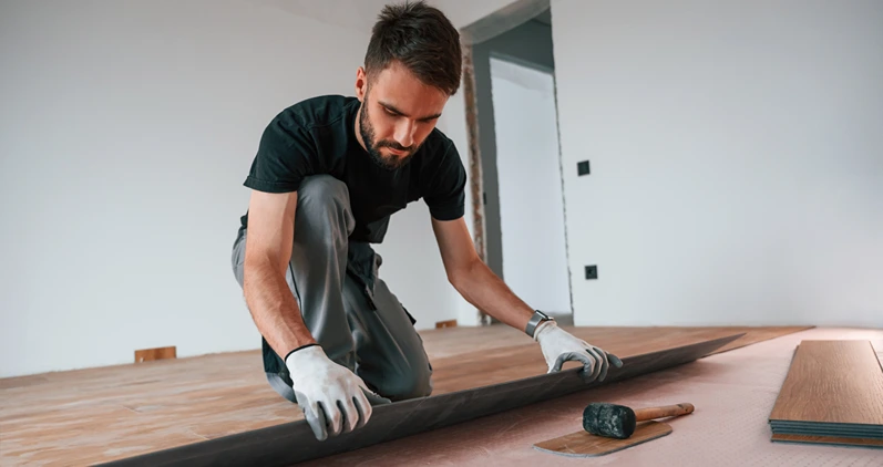 Hand work. Man is installing new laminated wooden floor.