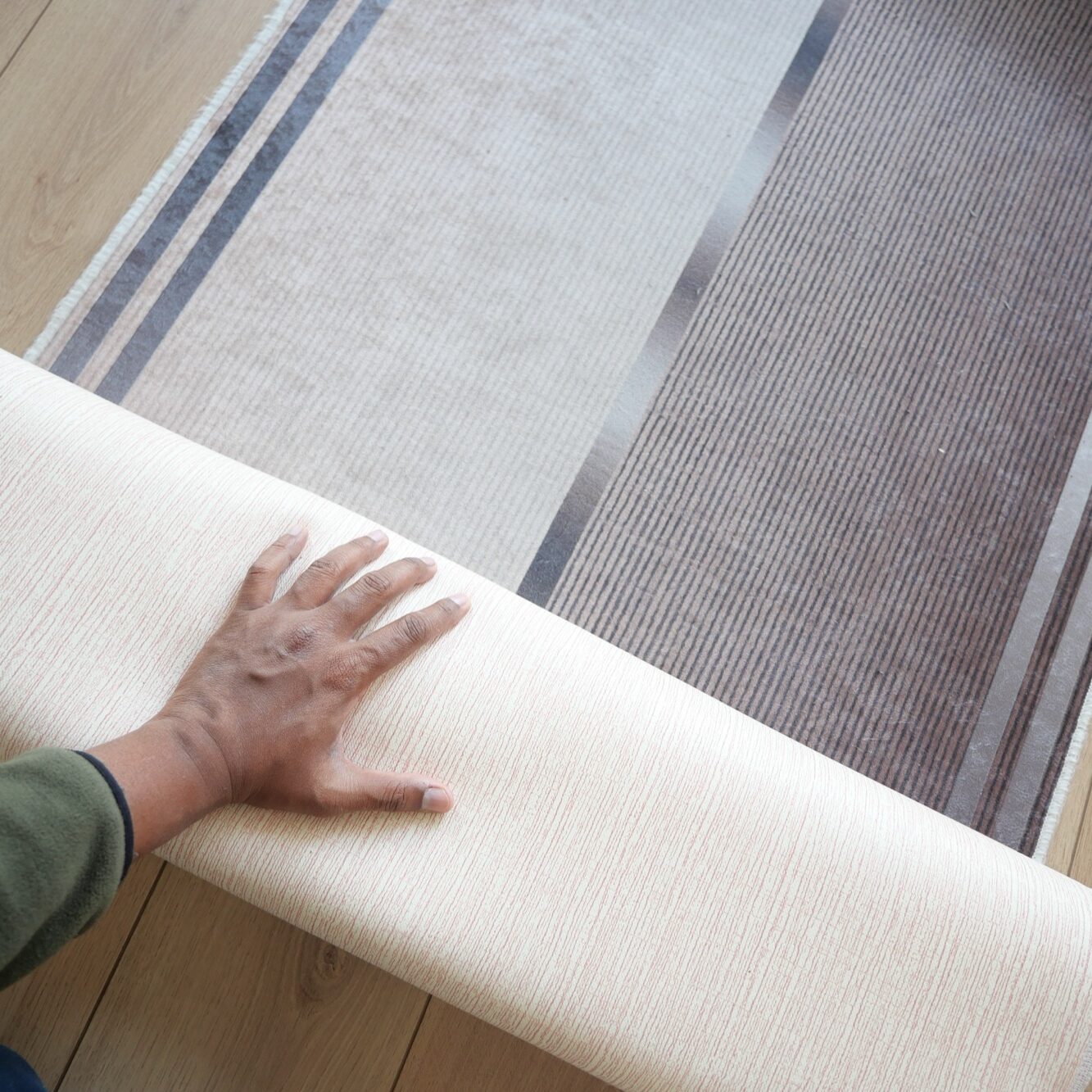Homeowner unrolling a new rug on hardwood floor in living room